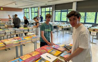 Schülerinnen und Schüler der Kursstufe stapeln Schulbücher auf Tische.