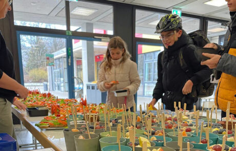 Eine Schülerin und ein Schüler suchen sich etwas Leckeres vom Büffet aus.