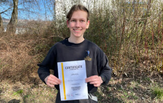 Henry Heinemann mit Urkunde vor einem Busch