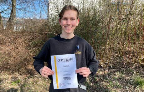 Neuroscience Olympiade Foto 1 Henry Heinemann mit Urkunde vor einem Busch